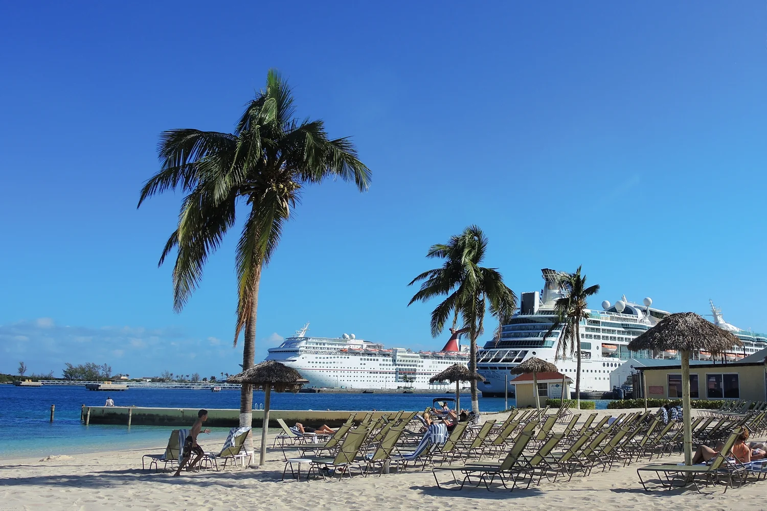 Cruise ships seen from a sandy beach across Nassau harbor