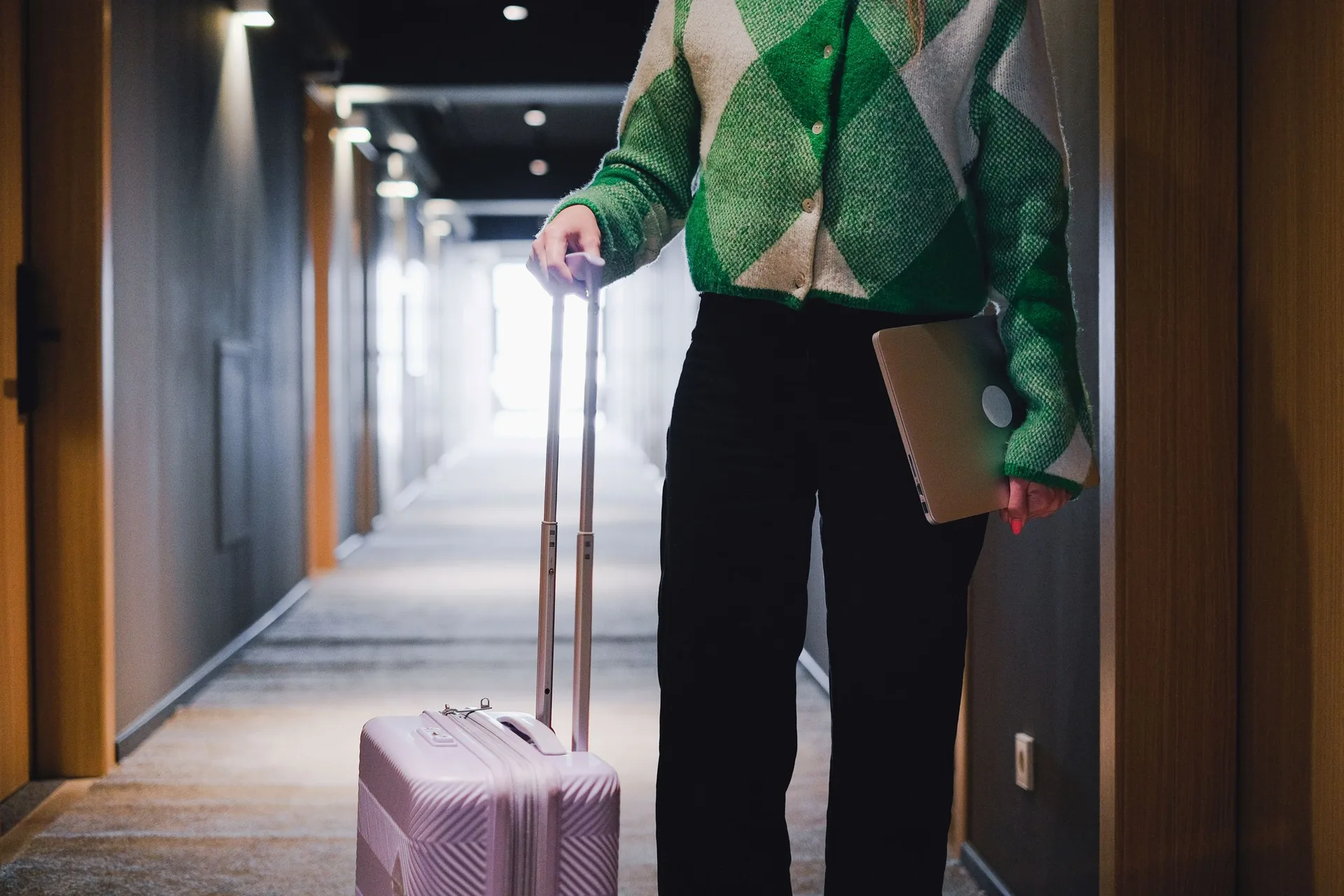 Traveler rolling a suitcase through a hotel corridor