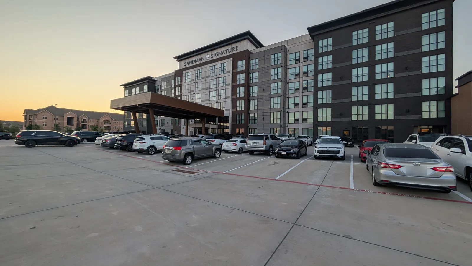 Sandman Signature Dallas-Las Colinas at sunset, with the porte-cochere and the front parking lot