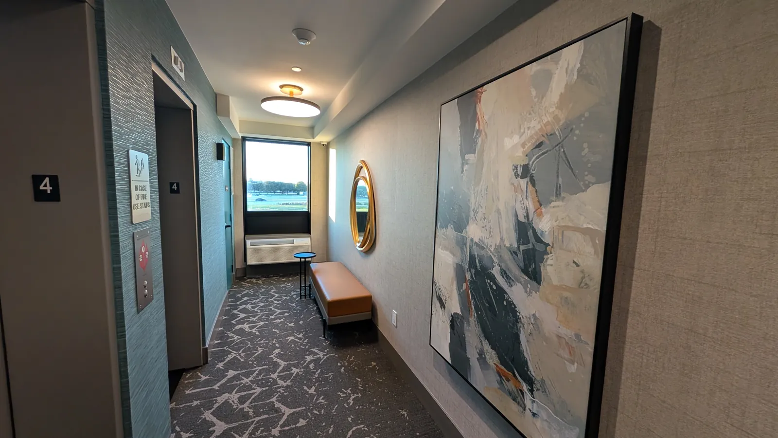 Fourth-floor elevator landing with a bench and wall art