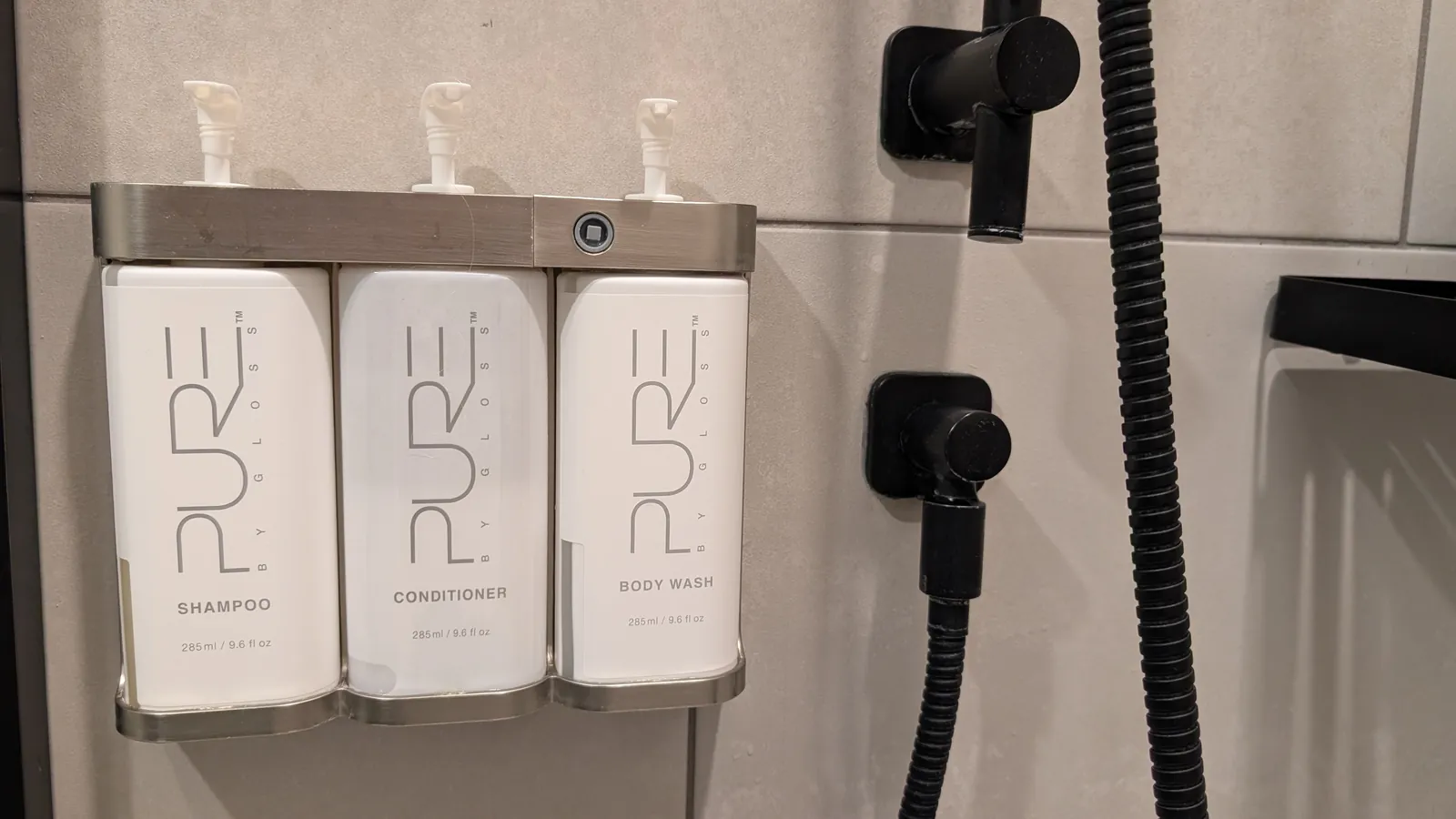 PURE shampoo, conditioner, and body wash dispensers in the shower.