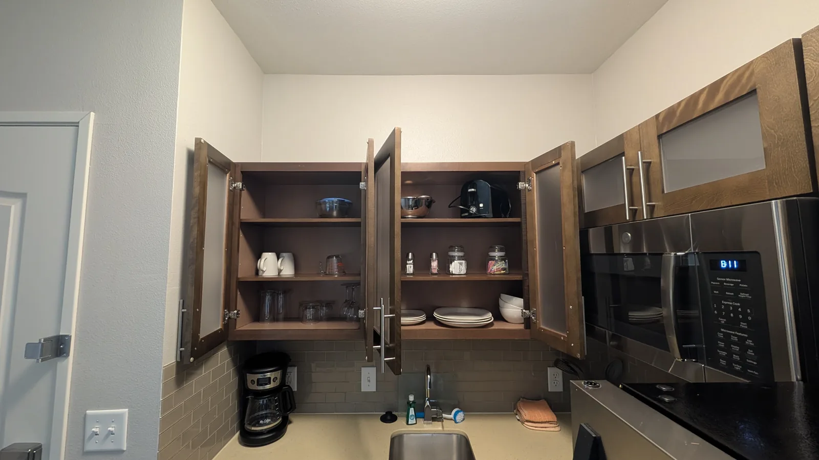 Open kitchen cabinets with a toaster, glasses, coffee cups, bowls, and plates